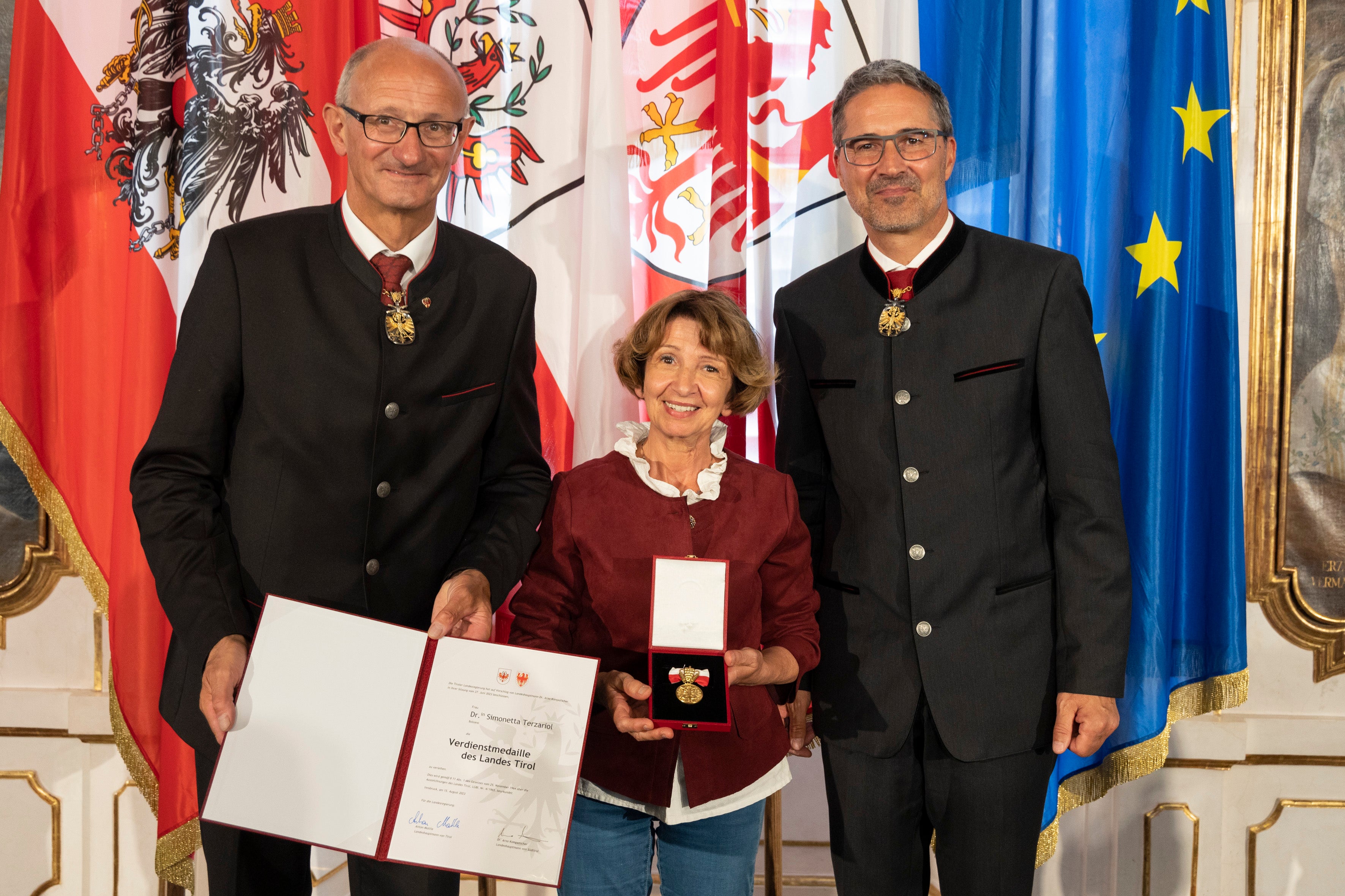 Come molti altri premiati, Simonetta Terzariol (Bolzano) - nella foto con i governatori Mattle (a sinistra) e Kompatscher (a destra) - ha ricevuto la medaglia al merito per il suo forte impegno nel settore sociale.
