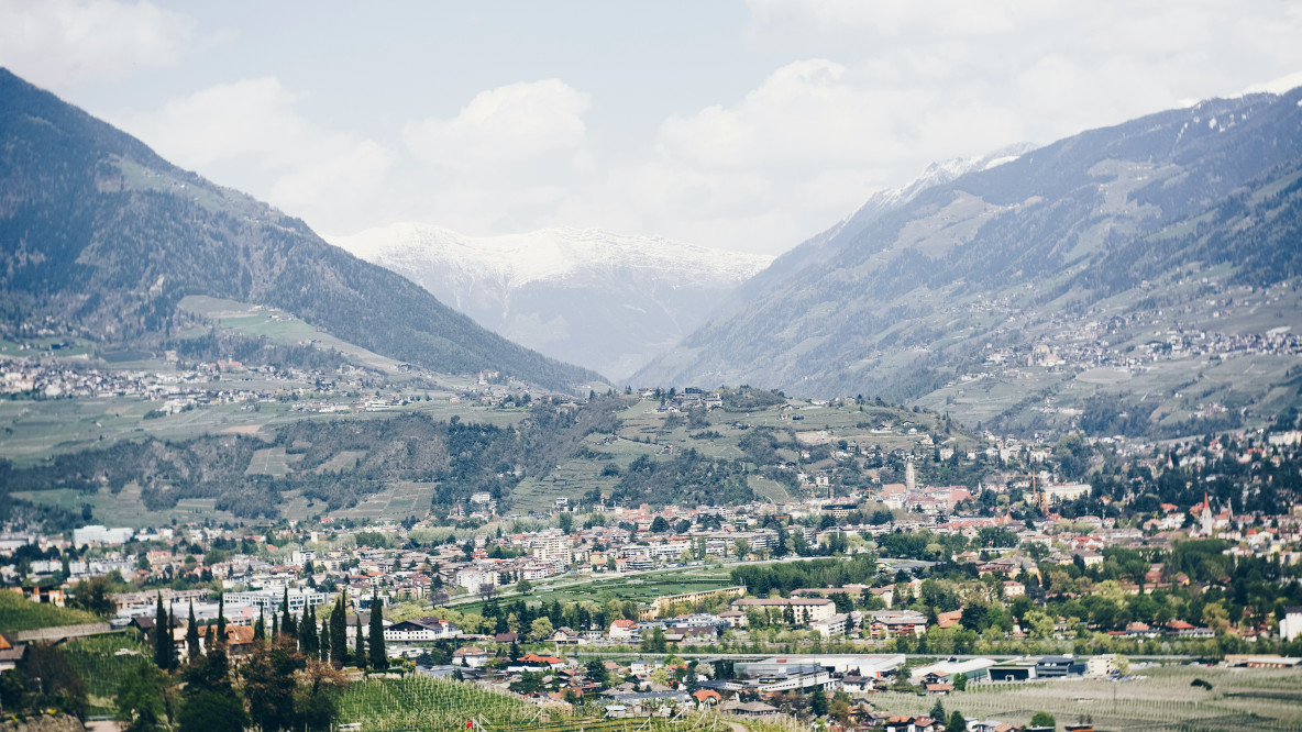 città con grattacieli che mostrano il campo verde e la montagna sotto cieli blu e bianchi