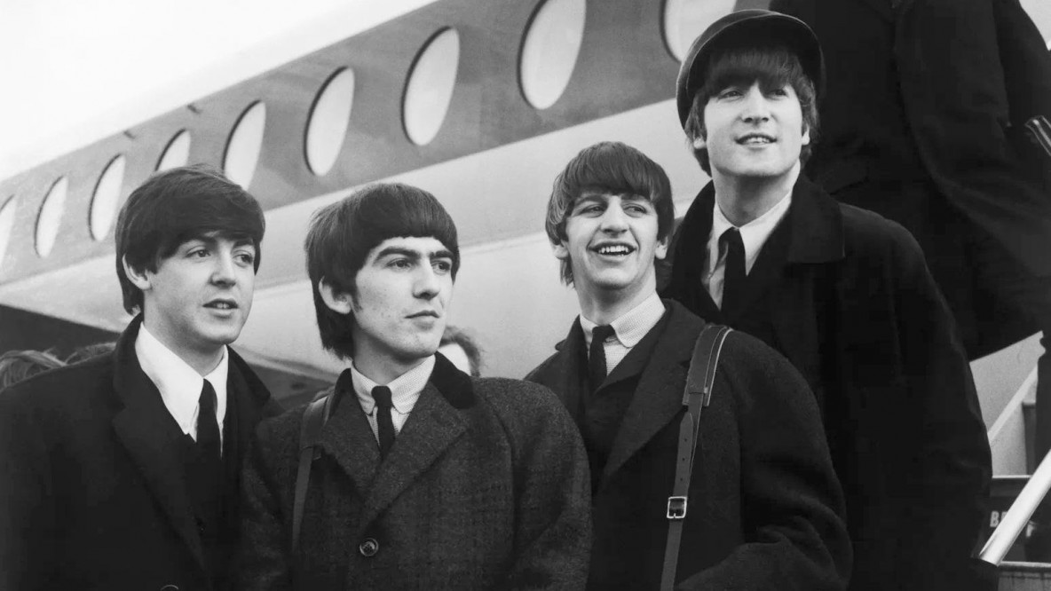 Die Beatles vor einem Flugzeug