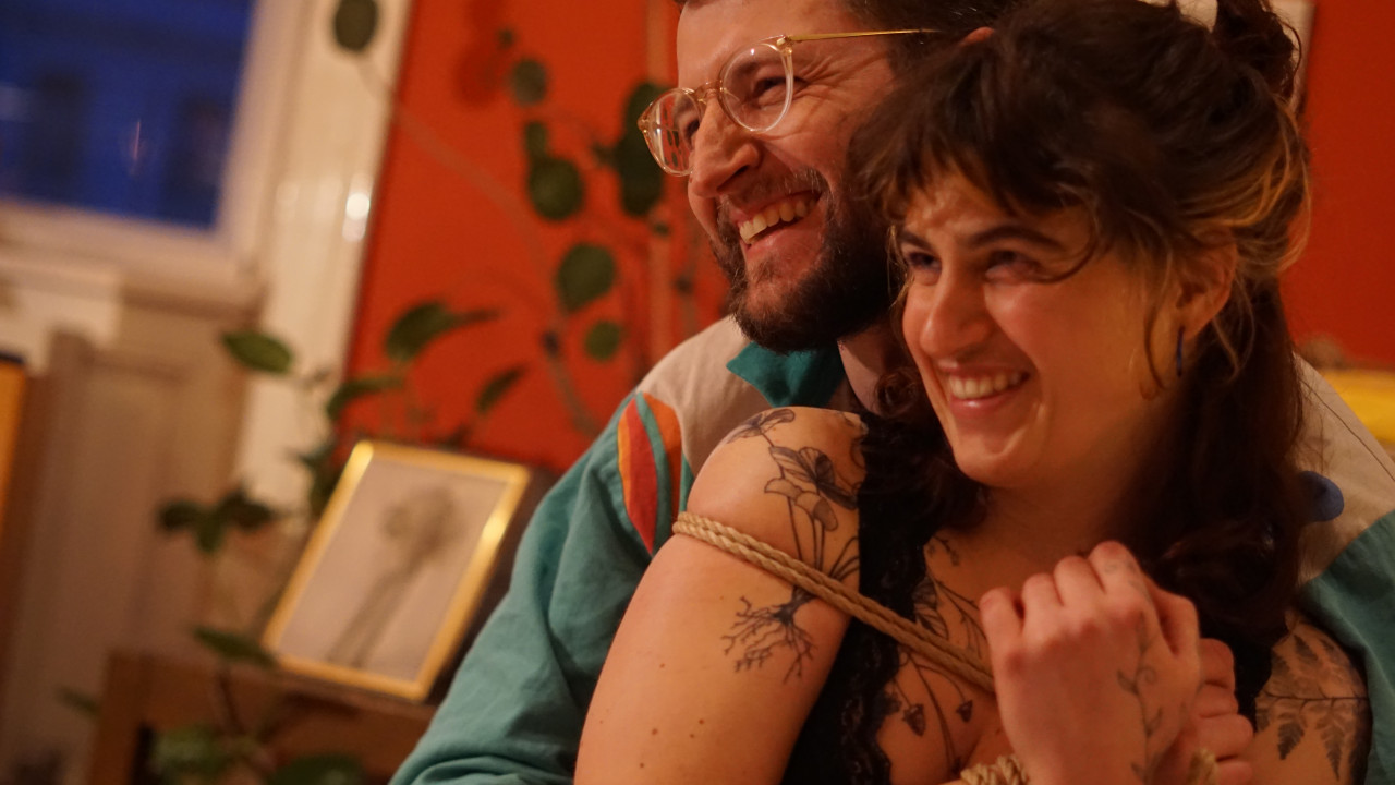 Das Bild zeigt Philipp und Lea, er umarmt sie von hinten. Sie hat ein Seil um gen Oberkörper gewickelt.