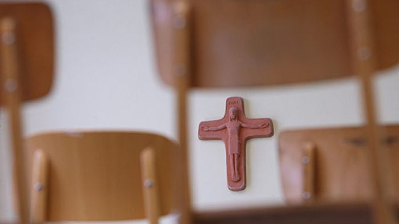 Schulbank mit Kreuz im Hintergrund 