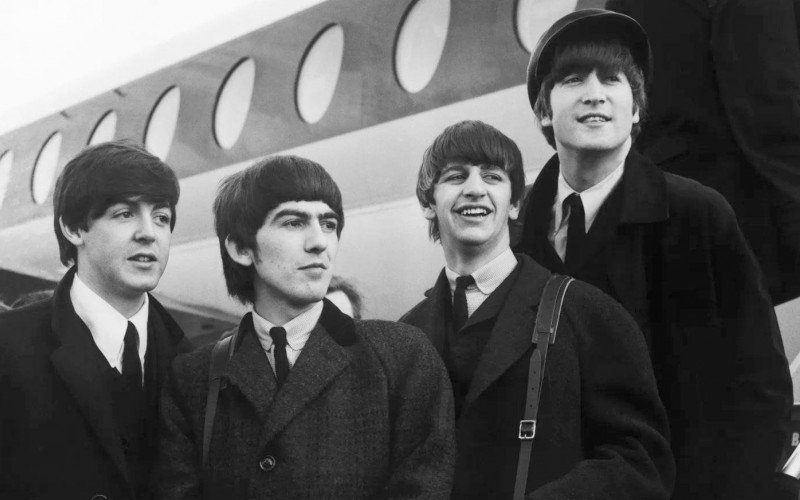 Die Beatles vor einem Flugzeug