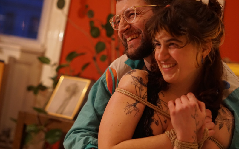 Das Bild zeigt Philipp und Lea, er umarmt sie von hinten. Sie hat ein Seil um gen Oberkörper gewickelt. 